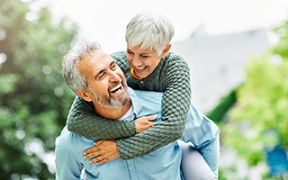 Middle-aged man and woman smiling with dental implants