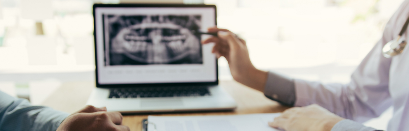 Having discussion over desk with dental X-ray in background