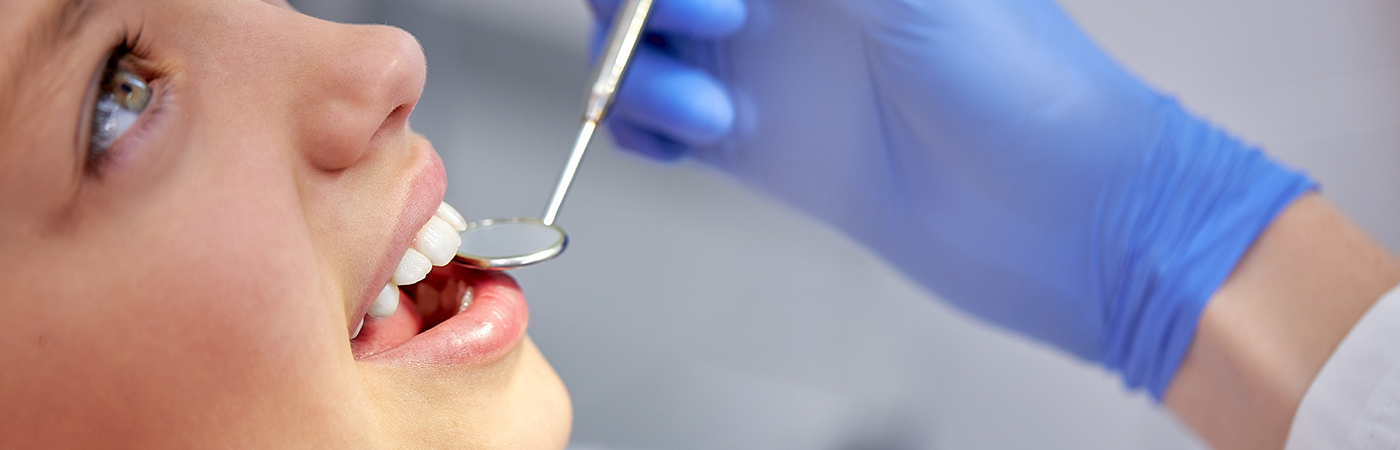 Female patient having teeth examined with dental mirror