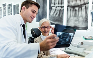 Dentist and patient smiling while looking at X-ray