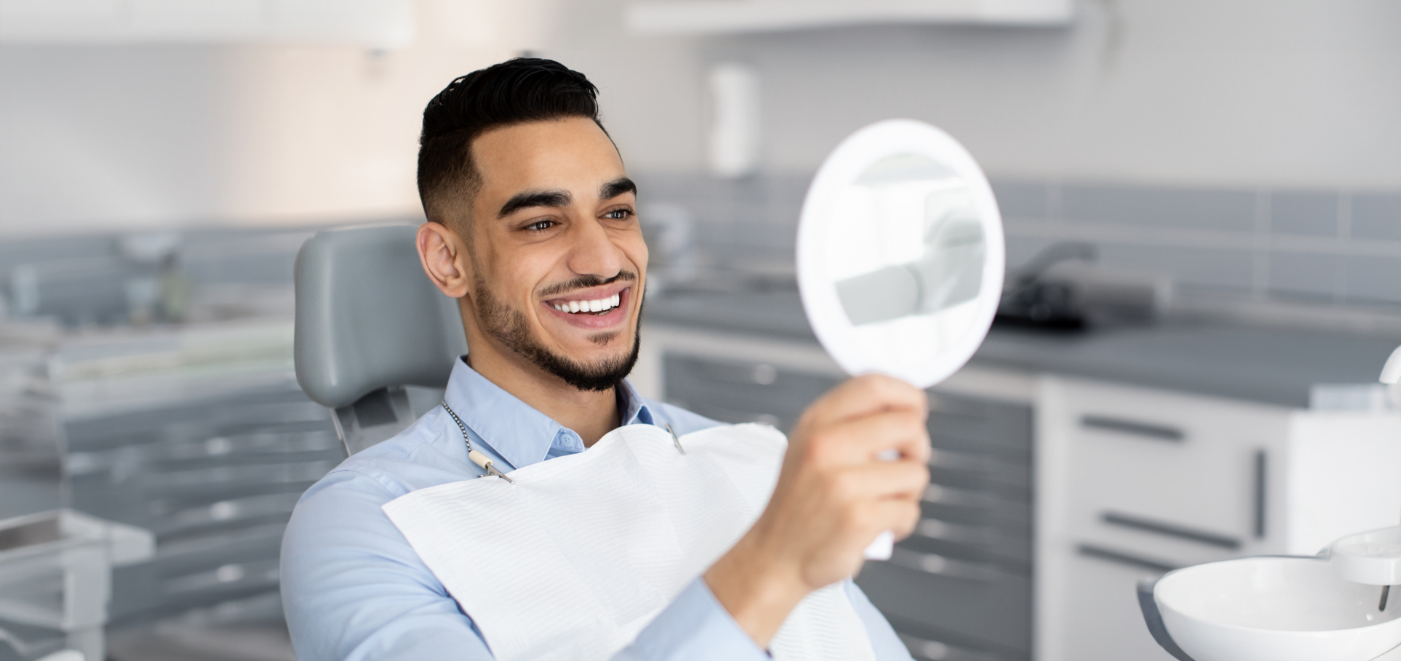 Male dental patient checking smile in mirror